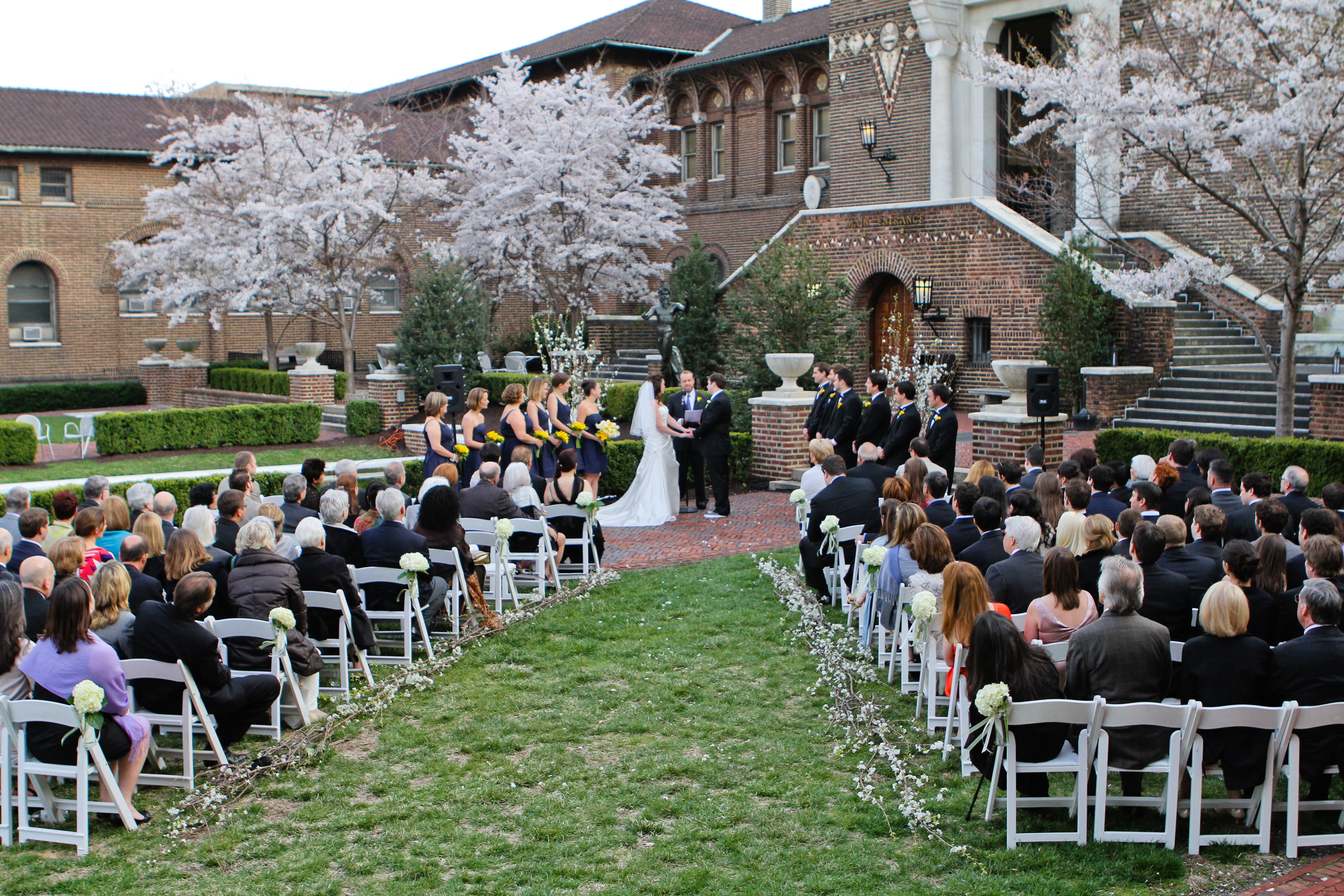 Outdoor wedding ceremony in a courtyard with guests seated on both sides at Penn Museum